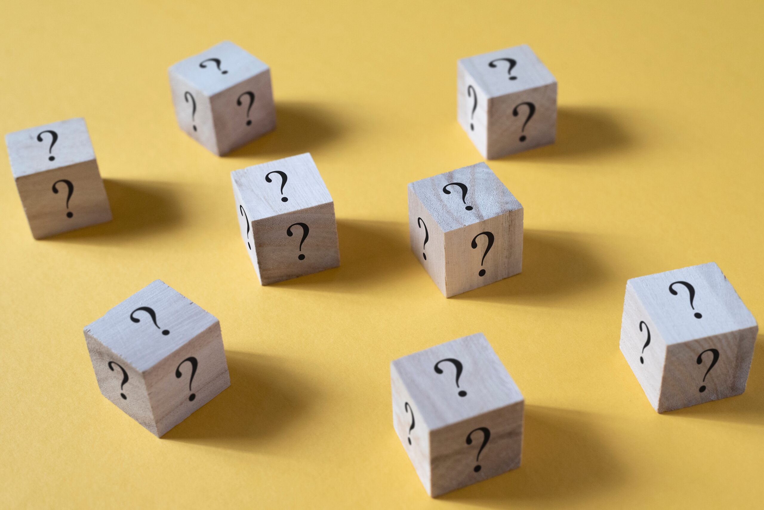 Wooden cube box with question mark on yellow background. Concept of questions, faq and uncertainty